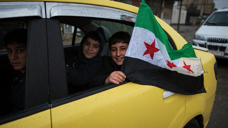 Locals cheer as Syrian army and security forces enter the city of Tabqa in the Raqqa countryside, after the Syrian government took control of the city on January 18, 2026.