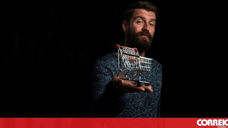 Homem segura carrinho de compras em miniatura