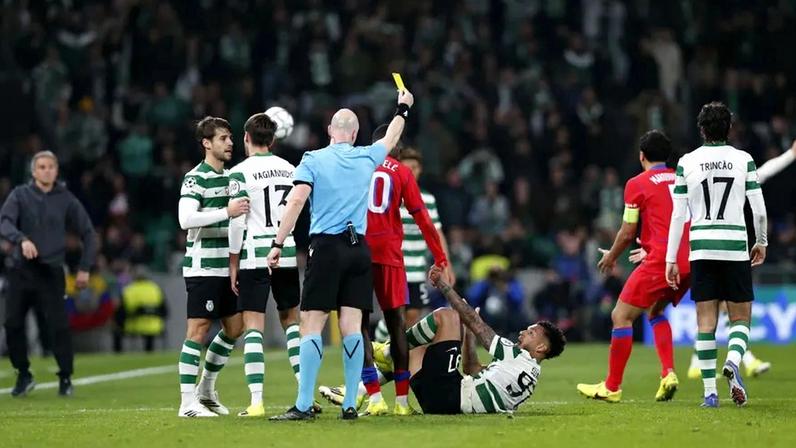 Árbitro Anthony Taylor mostra o cartão amarelo durante o Sporting-PSG