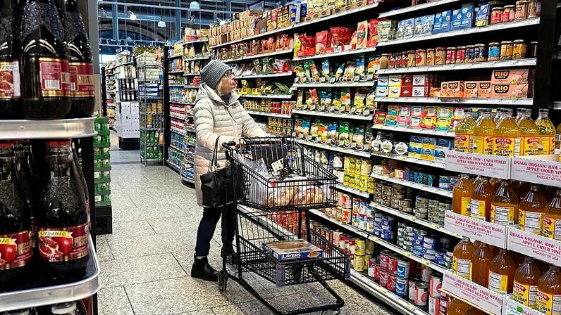 Mulher verifica preços enquanto faz compras num supermercado