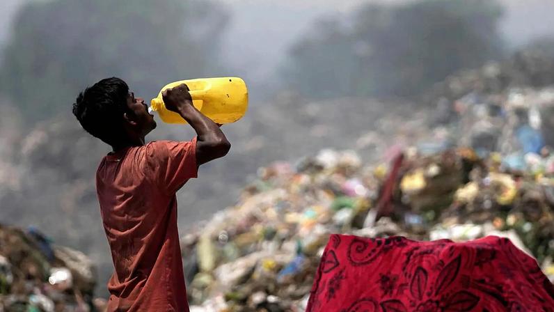 ARQUIVO - Catador de lixo bebe água enquanto trabalha durante uma onda de calor num aterro nos arredores de Jammu, Índia, quarta-feira, 19 de junho de 2024.