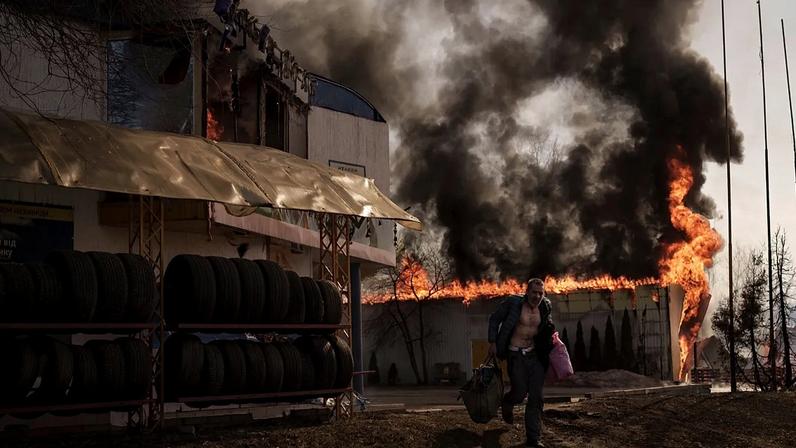 Um homem recupera artigos de uma loja que se incendiou durante um ataque russo em Kharkiv, na Ucrânia, na sexta-feira, 25 de março de 2022.