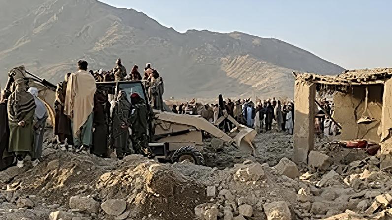 Residentes locais e trabalhadores da defesa civil observam enquanto um bulldozer limpa os escombros de uma casa atingida por um ataque do exército paquistanês além-fronteiras, no Afeganistão, domingo, 22 de fevereiro de 2026.