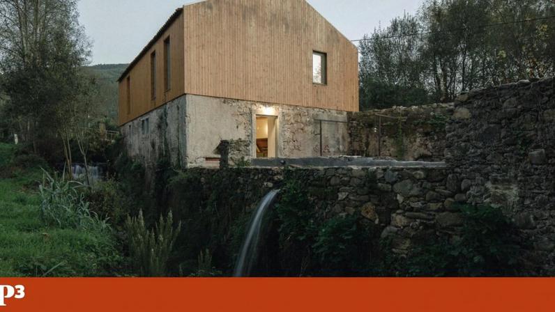 Vista exterior do Centro Interpretativo do Cereal, onde a nova estrutura em madeira assenta sobre as paredes de pedra do antigo moinho, integrando-se na paisagem natural de Santa Eufémia