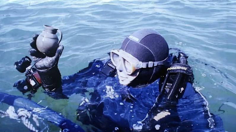 Mergulhador segura ânfora durante busca subaquática