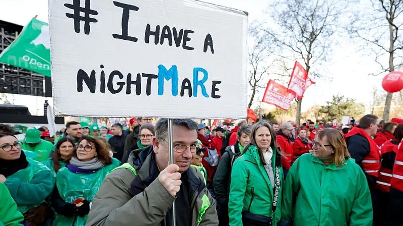 Um manifestante segura um cartaz durante uma ação de greve geral em Bruxelas, quinta‑feira, 12 de março de 2026.