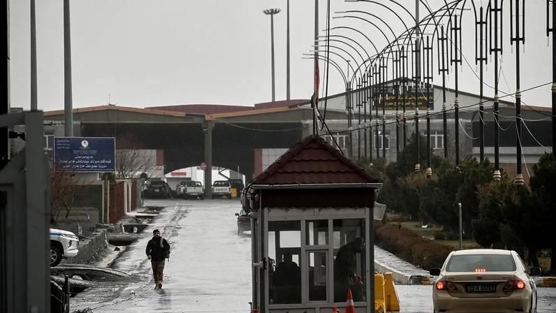 Um agente fronteiriço iraquiano caminha em direção ao lado iraquiano enquanto vários veículos atravessam o posto fronteiriço de Haji Omeran, entre o Irão e a Região Autónoma do Curdistão do Irão.