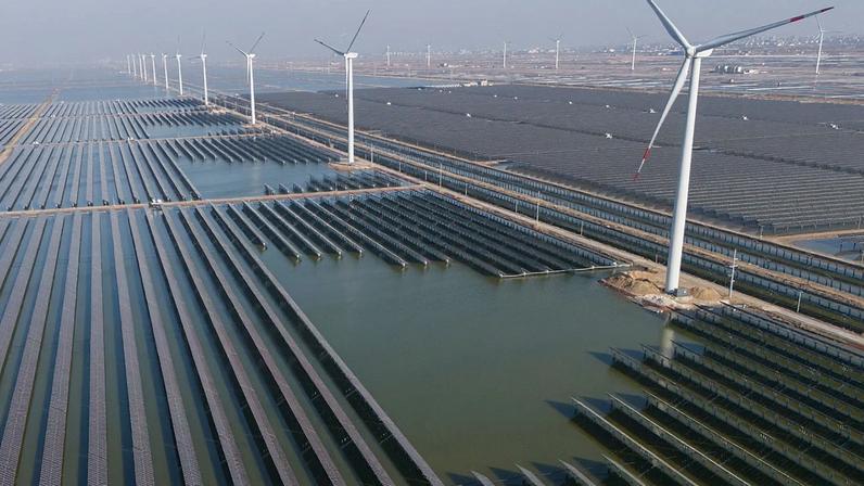 FOTO DE ARQUIVO - Aerogeradores funcionam junto de uma central solar perto de Weifang, na província de Shandong, no leste da China, a 22 de março de 2024
