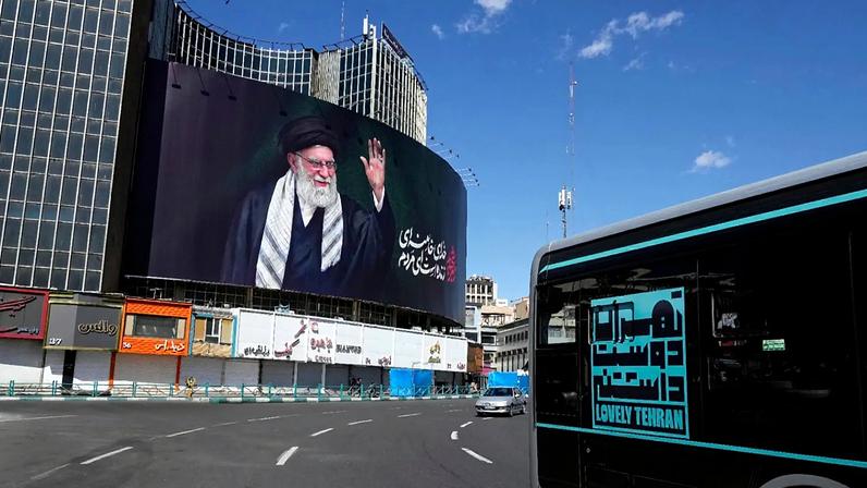 Teerão, Irão: Veículos passam por um cartaz com um retrato do falecido líder supremo iraniano, Ayatollah Ali Khamenei, que foi morto numa operação militar.