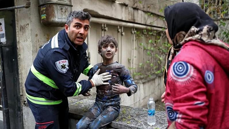 Um socorrista assiste um rapaz ferido após um ataque que atingiu um edifício residencial no âmbito da campanha militar israelo-americana em Teerão, Irão, sábado, 28 de março de 2026