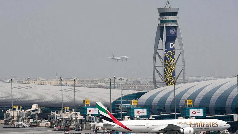 ARQUIVO - Um Boeing 777 da Emirates está na porta de embarque do Aeroporto Internacional do Dubai enquanto outro se prepara para aterrar na pista, no Dubai, Emirados Árabes Unidos, a 17 de agosto de 2022.