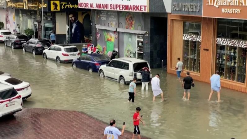 Pessoas atravessam ruas inundadas em Sharjah após forte chuva noturna