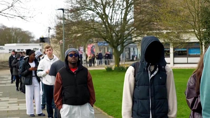 Fila de estudantes à espera de receber antibióticos no campus da Universidade de Kent
