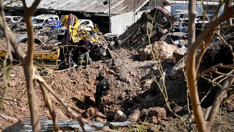 Forças de segurança israelitas analisam o local de um ataque com míssil iraniano em Eshtaol, no centro de Israel