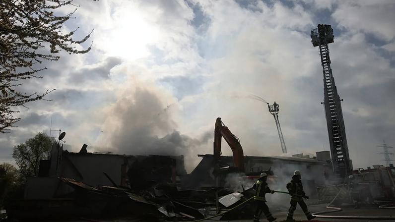 Os bombeiros utilizam maquinaria pesada para abrir caminho através de bolsas de brasas após um incêndio num clube noturno em Kehl, na Alemanha, no domingo, 29 de março.