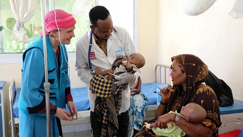 Um representante da UNICEF na Somália sorri para uma mãe de duas crianças gémeas subnutridas no Hospital de Referência de Dolow, no sul da Somália.