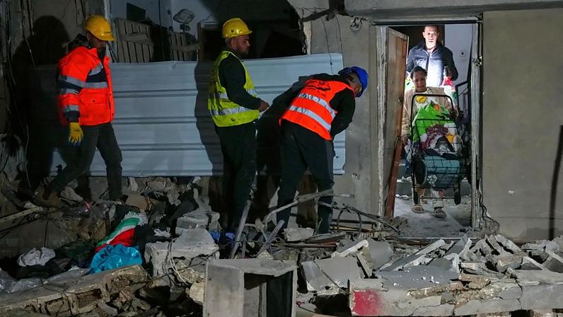 Moradores carregam pertences pessoais enquanto saem de um edifício danificado por um ataque de míssil em Tel Aviv, Israel, na madrugada de sábado, 28 de março de 2026
