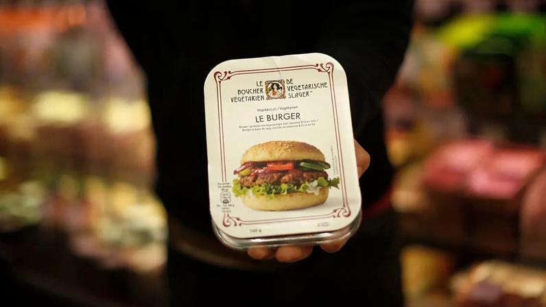 Empregado de loja mostra hambúrguer à base de plantas numa cadeia de supermercados em Bruxelas, sexta-feira, 23 de outubro de 2020