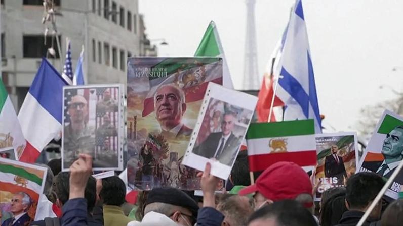 Manifestantes em Paris brandem retratos do filho do último Xá do Irão, Reza Pahlavi, bandeiras da monarquia iraniana e bandeiras francesas e israelitas, 7 de março de 2026.