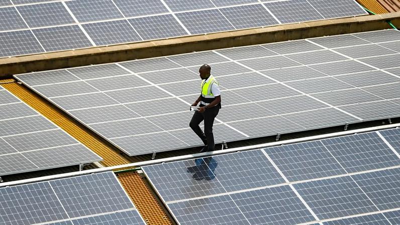 FOTO DE ARQUIVO - O técnico da CP Solar, Mark Munyua, inspeciona painéis solares no telhado de uma empresa em Nairobi, Quénia, em 1 de setembro de 2023