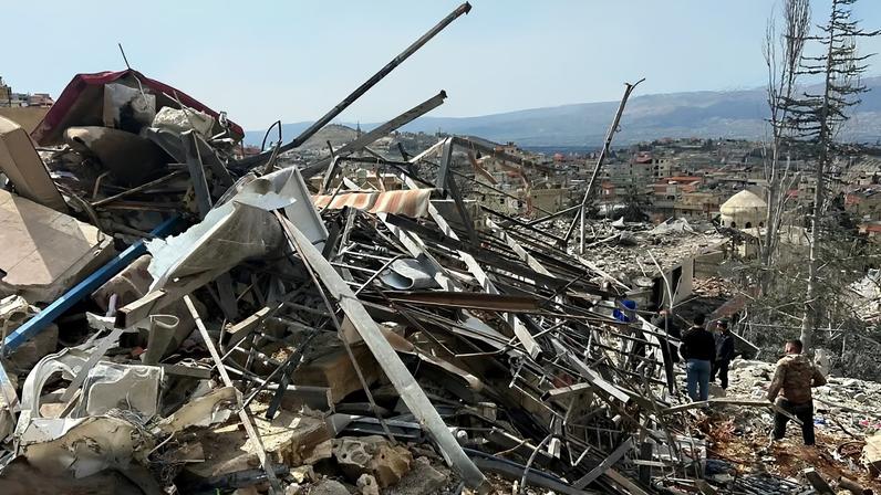 Pessoas verificam os danos causados pelos ataques aéreos israelitas, sábado, 7 de março de 2026, na aldeia de Nabi Chit, no leste do Líbano, na sexta-feira.