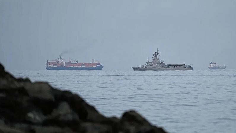 Um navio da marinha dos EAU navega ao lado de um navio de carga no Estreito de Ormuz, visto de Khor Fakkan, 11 de março de 2026