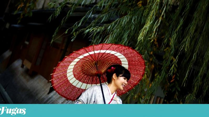 Uma mulher, vestida com um quimono tradicional japonês, posa para os turistas em Quioto, no Japão