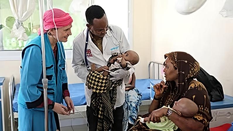 Um representante da UNICEF na Somália sorri para uma mãe de duas crianças gémeas subnutridas no Hospital de Referência de Dolow, no sul da Somália.