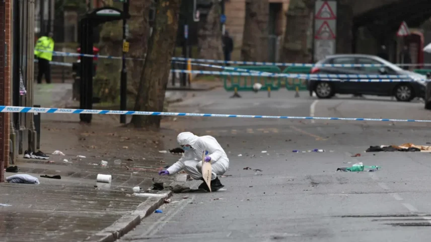 A police forensic officer fills an evidence bag while working amongst a variety of personal items seen covering the road, inside a cordon set up on Friar Gate in central Derby, central England on March 29, 2026, following an incident the night before where a vehicle was driven into pedestrians. British police said they arrested a man after a car struck several pedestrians in a city in central England on Saturday night, leaving some victims seriously injured. (Photo by Darren Staples / AFP)