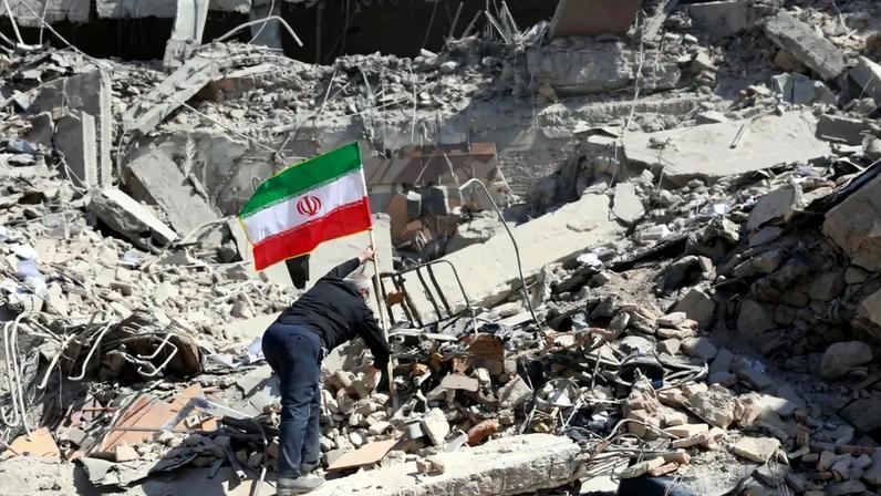 Homem coloca bandeira do Irão no meio de destroços em Teerão