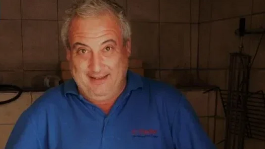 Retrato de um homem sorridente com uma camisa azul num espaço interior