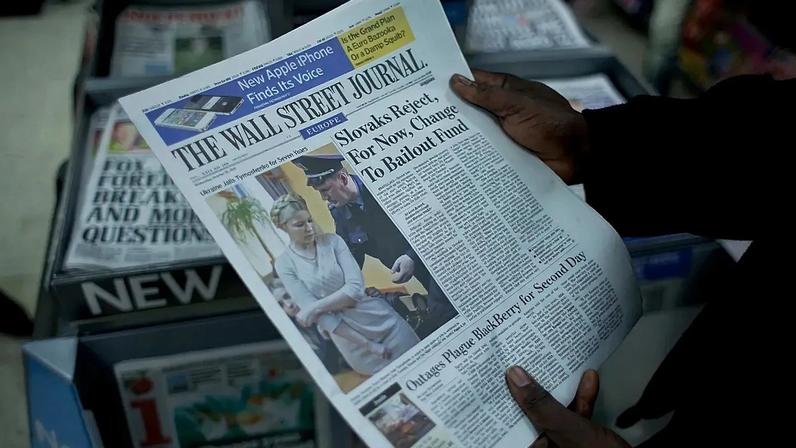 Um trabalhador posa para fotografias segurando um exemplar do Wall Street Journal em Londres, 12 de outubro de 2011