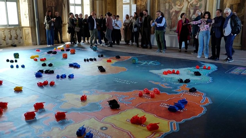 Pessoas reúnem-se em redor de uma versão gigante do jogo Risk em exposição
