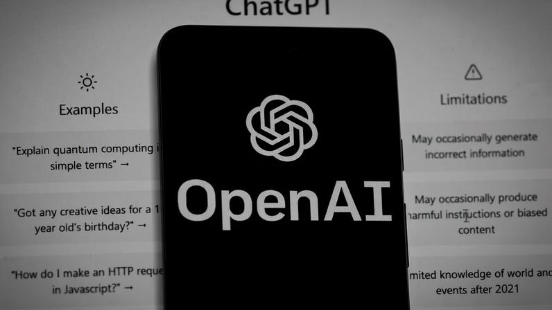 Vê-se o logótipo da OpenAI num telemóvel, em frente a um ecrã de computador que mostra a página inicial do ChatGPT, sexta-feira, 17 de março de 2023, em Boston.