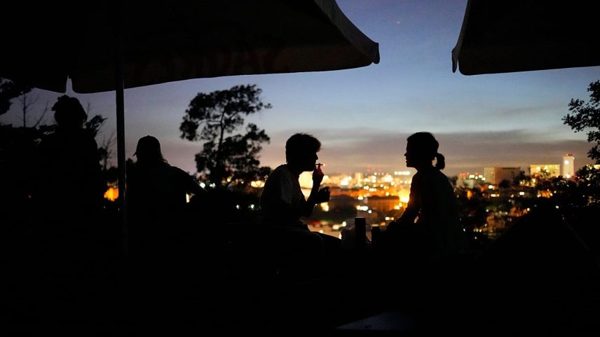 Pessoas sentadas na esplanada de um bar fechado no miradouro do Monte Agudo, com vista para Lisboa, durante um corte de energia a nível nacional, na segunda-feira, 28 de abril