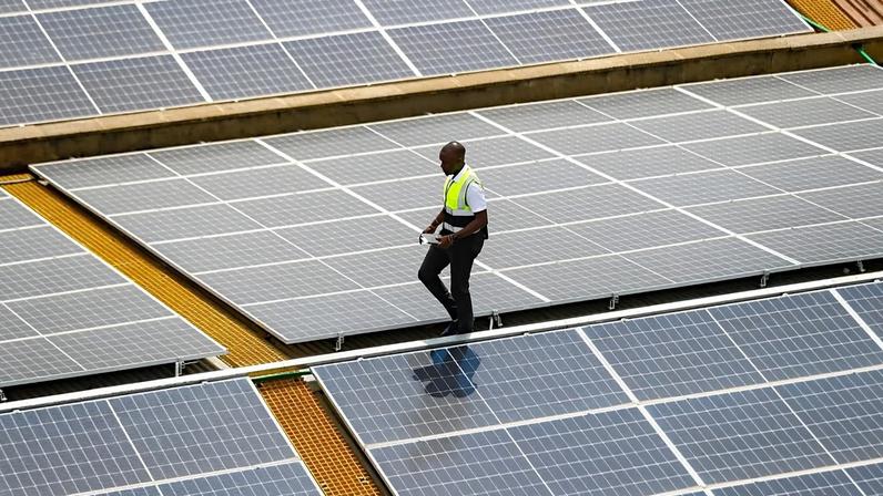 Mark Munyua, técnico da CP Solar, inspeciona painéis solares no telhado de uma empresa em Nairobi, Quénia, 1 de setembro de 2023.
