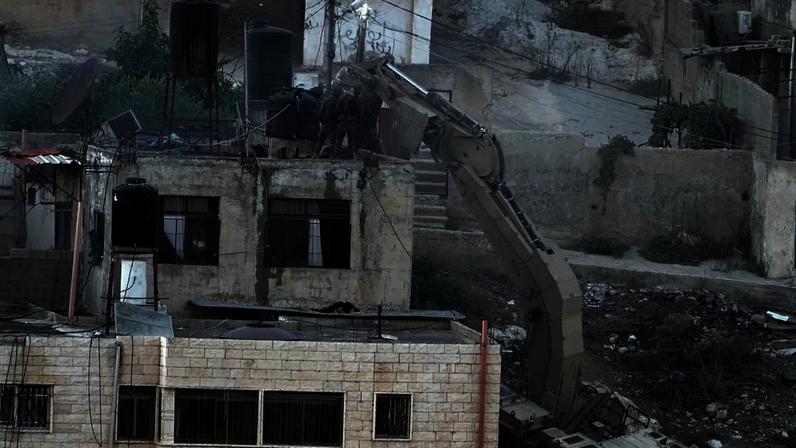 Soldados israelitas olham para um telhado onde dois corpos jazem imóveis na cidade de Qabatiya, na Cisjordânia, durante uma rusga, quinta-feira, 19 de setembro de 2024. (AP Photo)