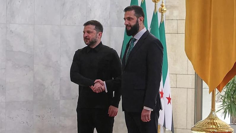 O Presidente sírio Ahmad al-Sharaa, à direita, aperta a mão ao Presidente ucraniano Volodymyr Zelenskyy antes de uma reunião no Palácio do Povo em Damasco, Síria, a 5 de abril,