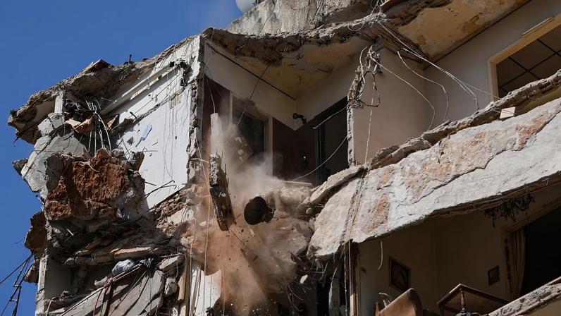 Trabalhadores removem os escombros enquanto as equipas de salvamento continuam a procurar uma mulher e uma rapariga desaparecidas num edifício destruído em Beirute, 13 de abril de 2026