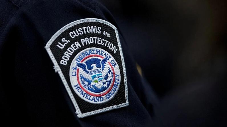 ARQUIVO - Um agente aduaneiro usa emblema da agência norte‑americana de Alfândega e Proteção de Fronteiras, 27 de outubro de 2017, no Aeroporto John F. Kennedy, em Nova Iorque