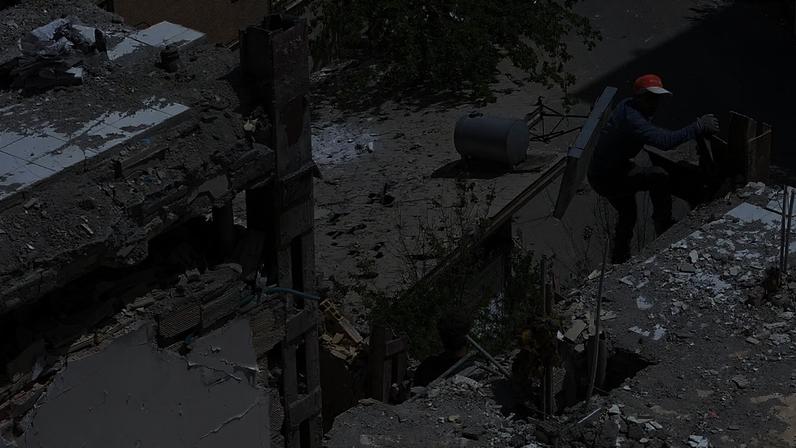 Um trabalhador sobe a um edifício residencial danificado no sudeste de Teerão, a 14 de abril de 2026