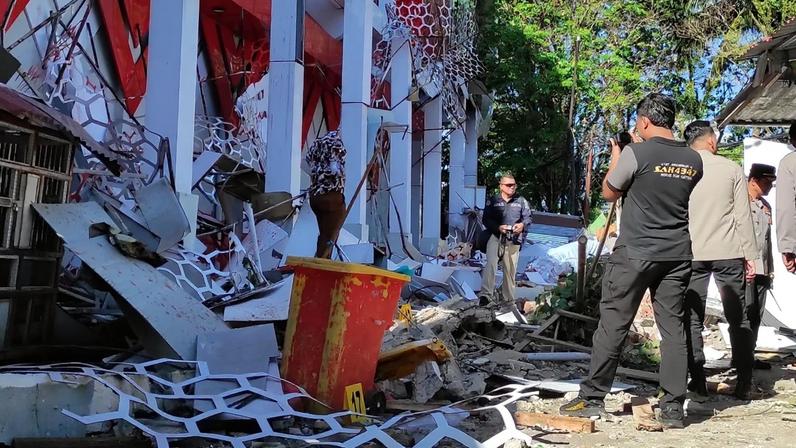 Curiosos reúnem-se enquanto agentes da polícia inspecionam um edifício danificado na sequência de um terramoto em Manado, Sulawesi do Norte, Indonésia