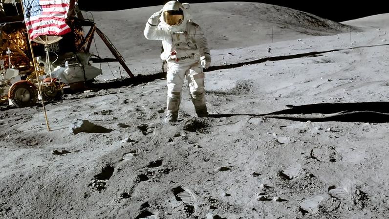 Vista do módulo lunar da estação (LM), do piloto do módulo lunar (LMP), Charles M. Duke Jr., e da bandeira