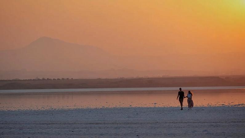 Casal passeia junto à lagoa salgada ao pôr do sol, na cidade costeira de Larnaca, no sudeste da ilha mediterrânica de Chipre, em 5 de setembro de 2022.