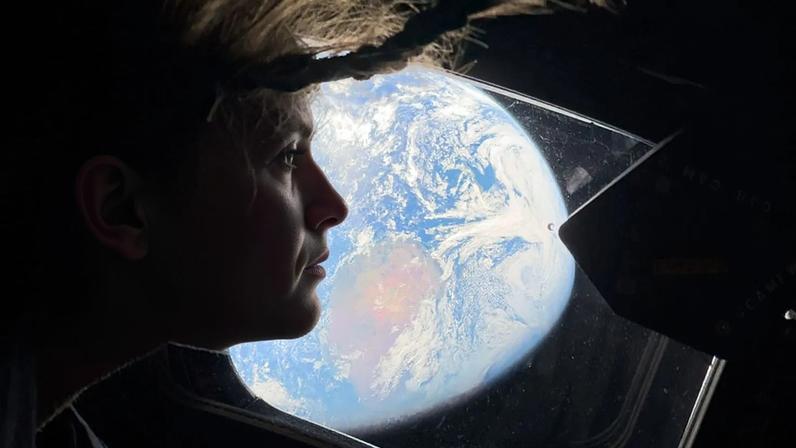 A astronauta e especialista da missão Artemis II, Christina Koch, espreita por uma das janelas da cabina principal da nave espacial Orion, olhando para a Terra, quinta-feira, 2 de abril de 2026