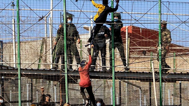ARQUIVO - Migrantes sobem as vedações que separam o enclave espanhol de Melilla de Marrocos em Melilla, Espanha, sexta-feira, 24 de junho de 2022.