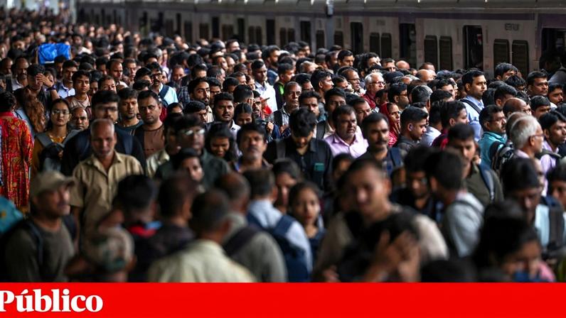Centenas de pessoas aguardam a chegada do comboio numa estação de caminhos de ferro de Bombaim, na Índia