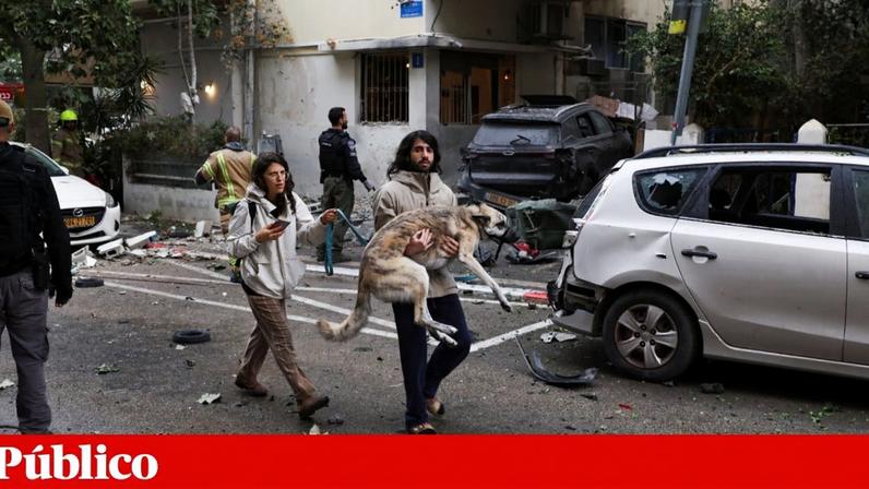 Um homem segura um cão em Telavive depois de soarem os alarmes perante um ataque iraniano, a 1 de Abril de 2026