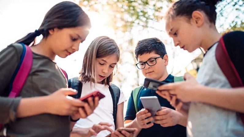 Grupo de jovens observa redes sociais em telemóveis