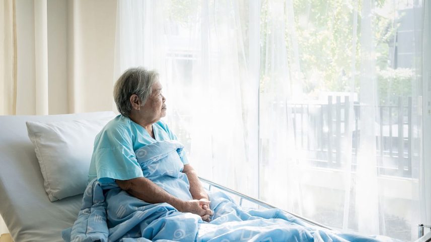 Uma mulher sentada na cama de hospital olha para a luz lá fora. Após infeção por hantavírus, muitos continuam a sofrer problemas físicos e mentais duradouros.